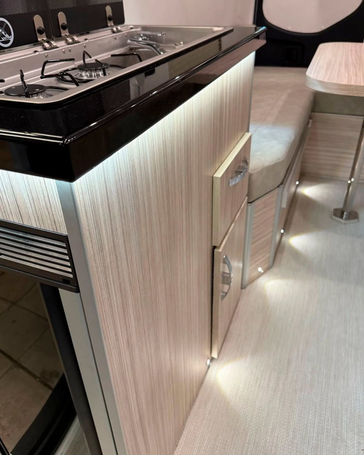 Detail of the black worktop over a light oak laminate unit with LED lighting underneath