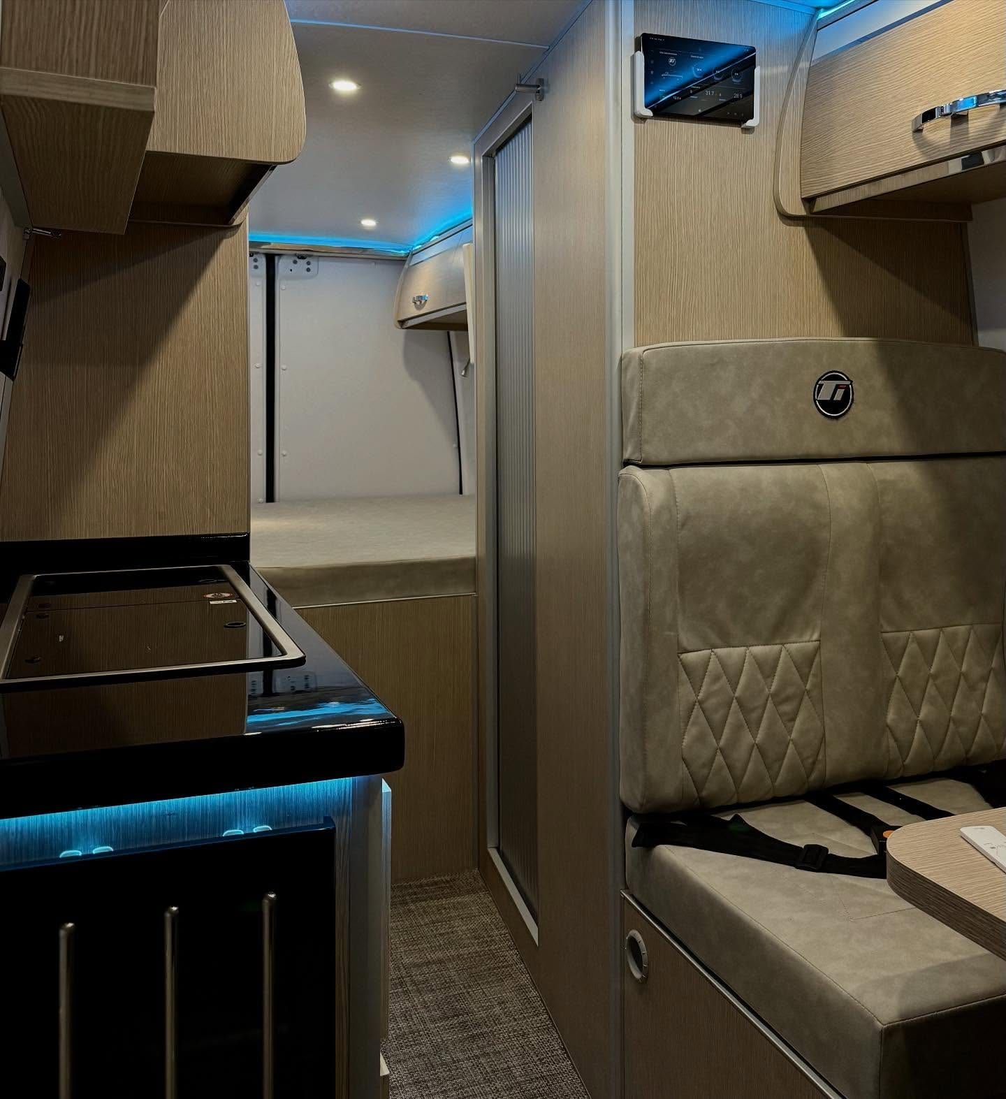 Interior de la Sprinter equipada por Taller Italia: cocina, comedor y baño, con la cama al fondo