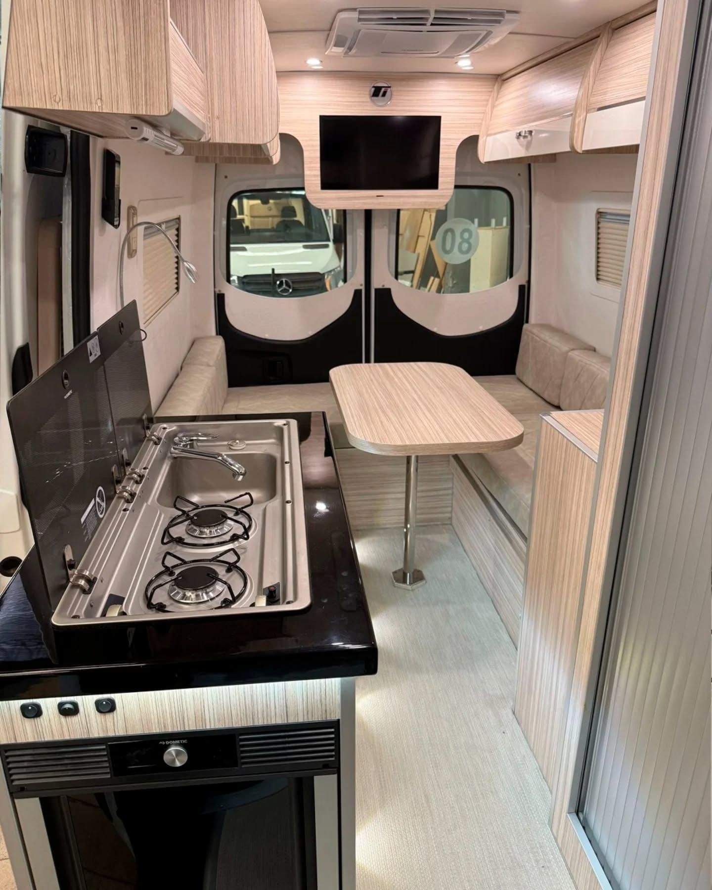 Galley with the gas hob lid raised, stainless sink and the dinette table