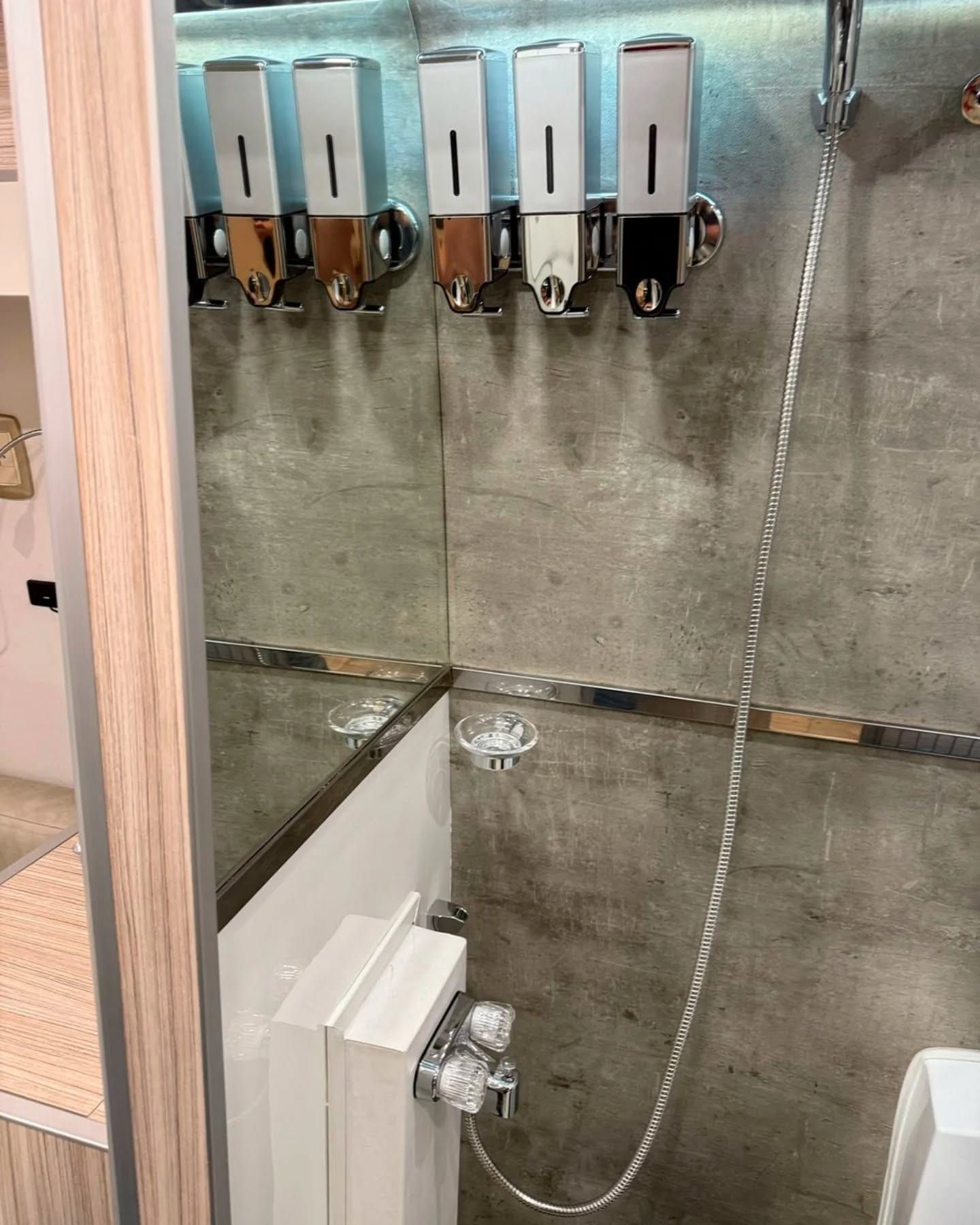 Washroom with concrete-effect finish, mirrors and wall-mounted dispensers