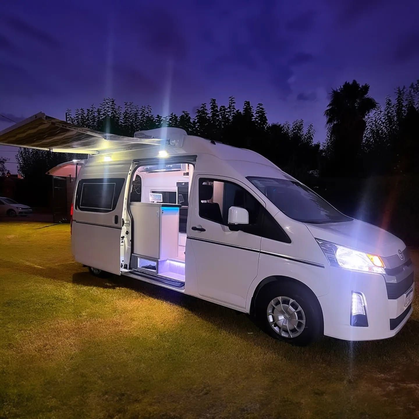 Toyota Hiace equipada por Taller Italia, de noche, con el toldo desplegado y las luces encendidas