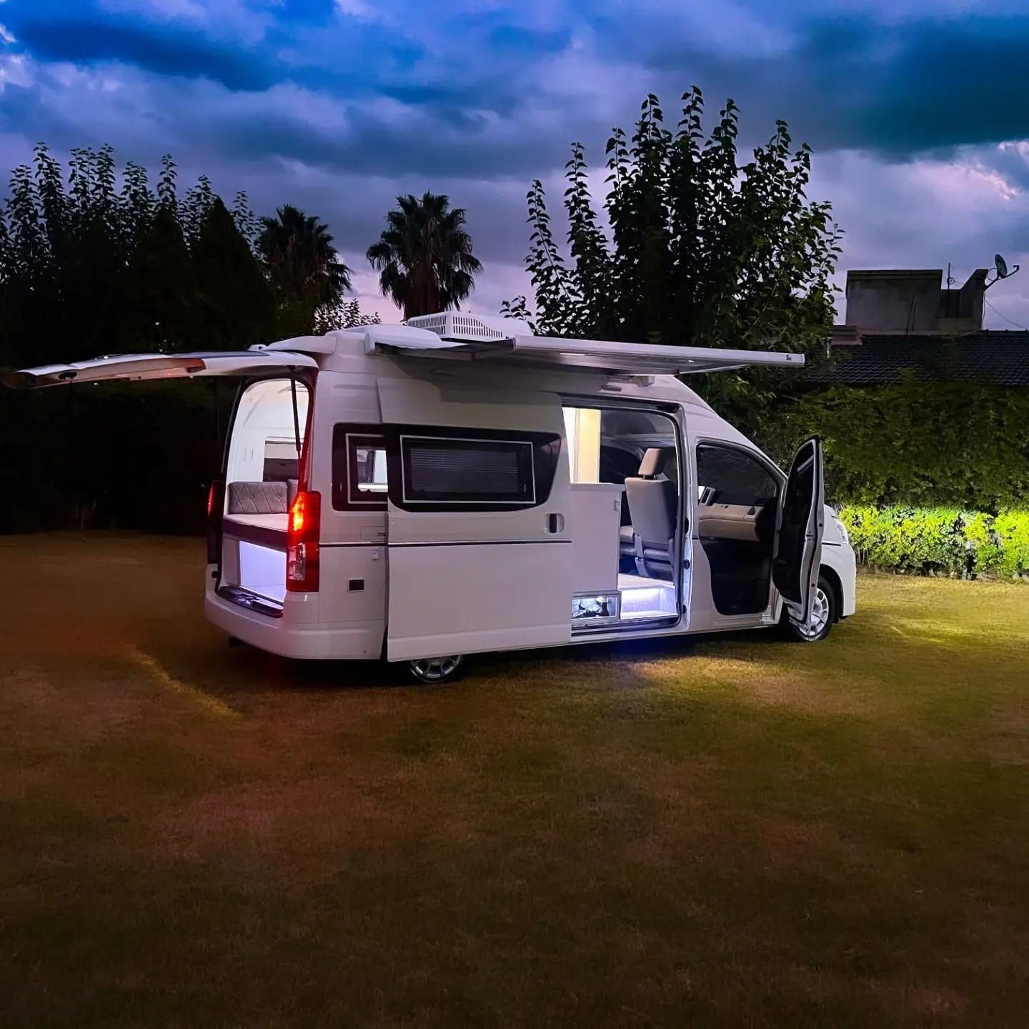 Vista trasera de la Toyota Hiace equipada, con puertas abiertas e interior iluminado