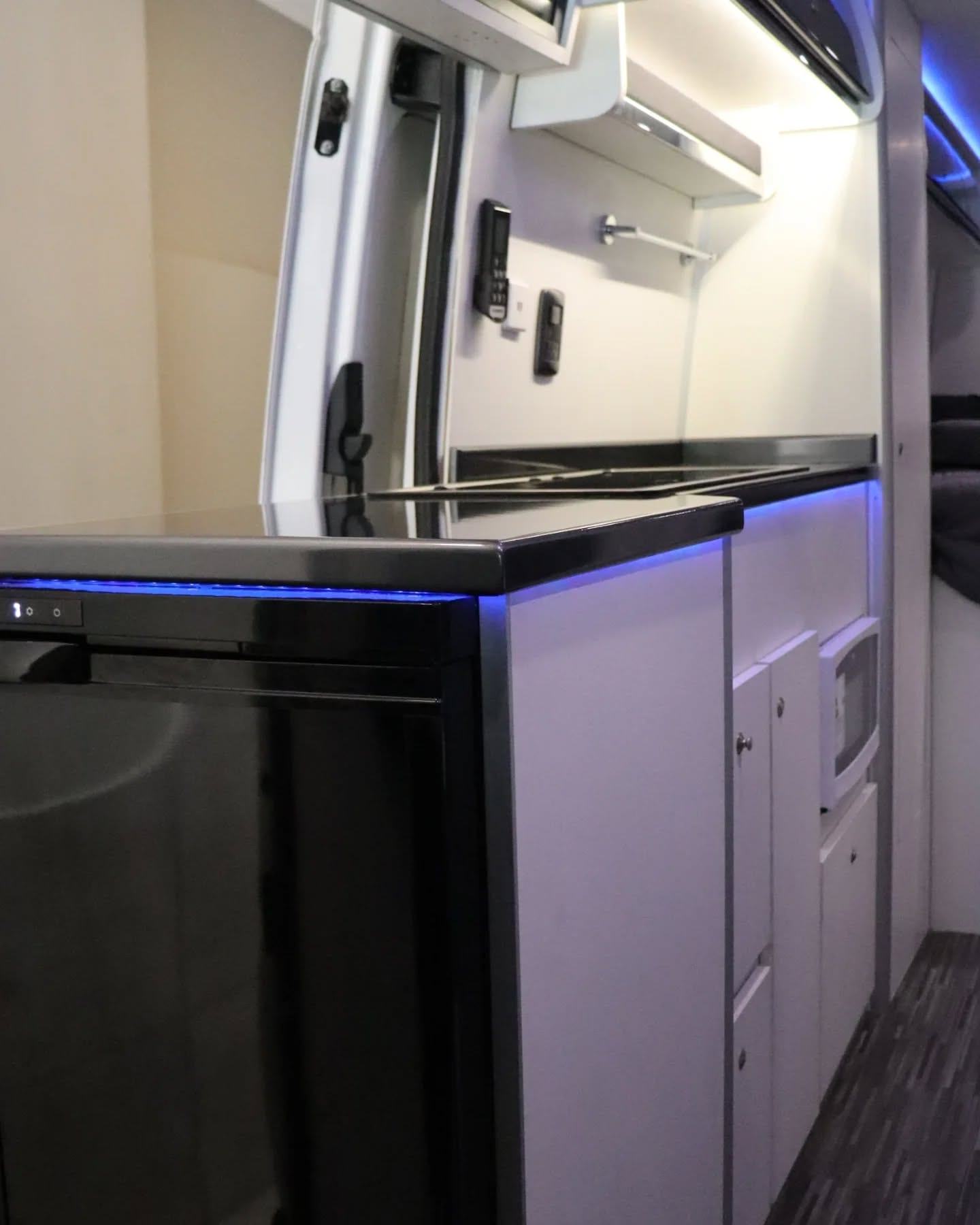 Cocina en línea de la Sprinter 517 XL, con mesada negra, heladera de columna y luz LED azul