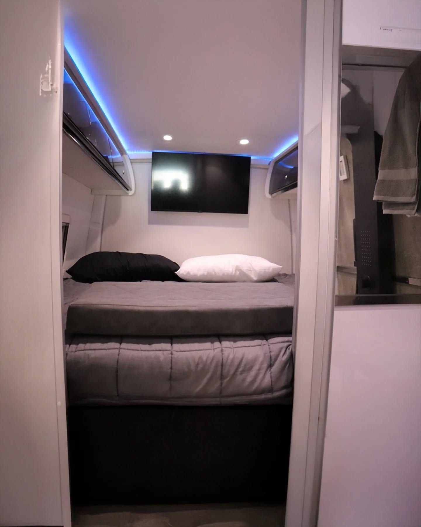 Dormitorio cerrado del fondo con cama tendida, TV propia y acceso al baño