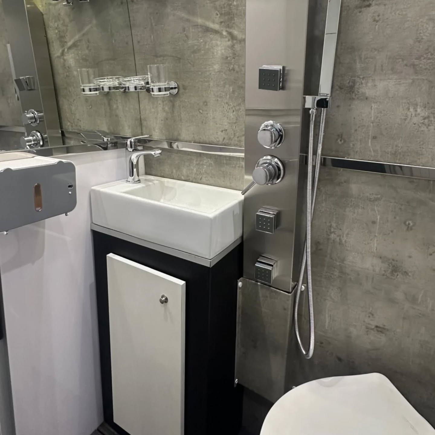 Washroom with countertop basin, shower column with body jets and facing mirrors