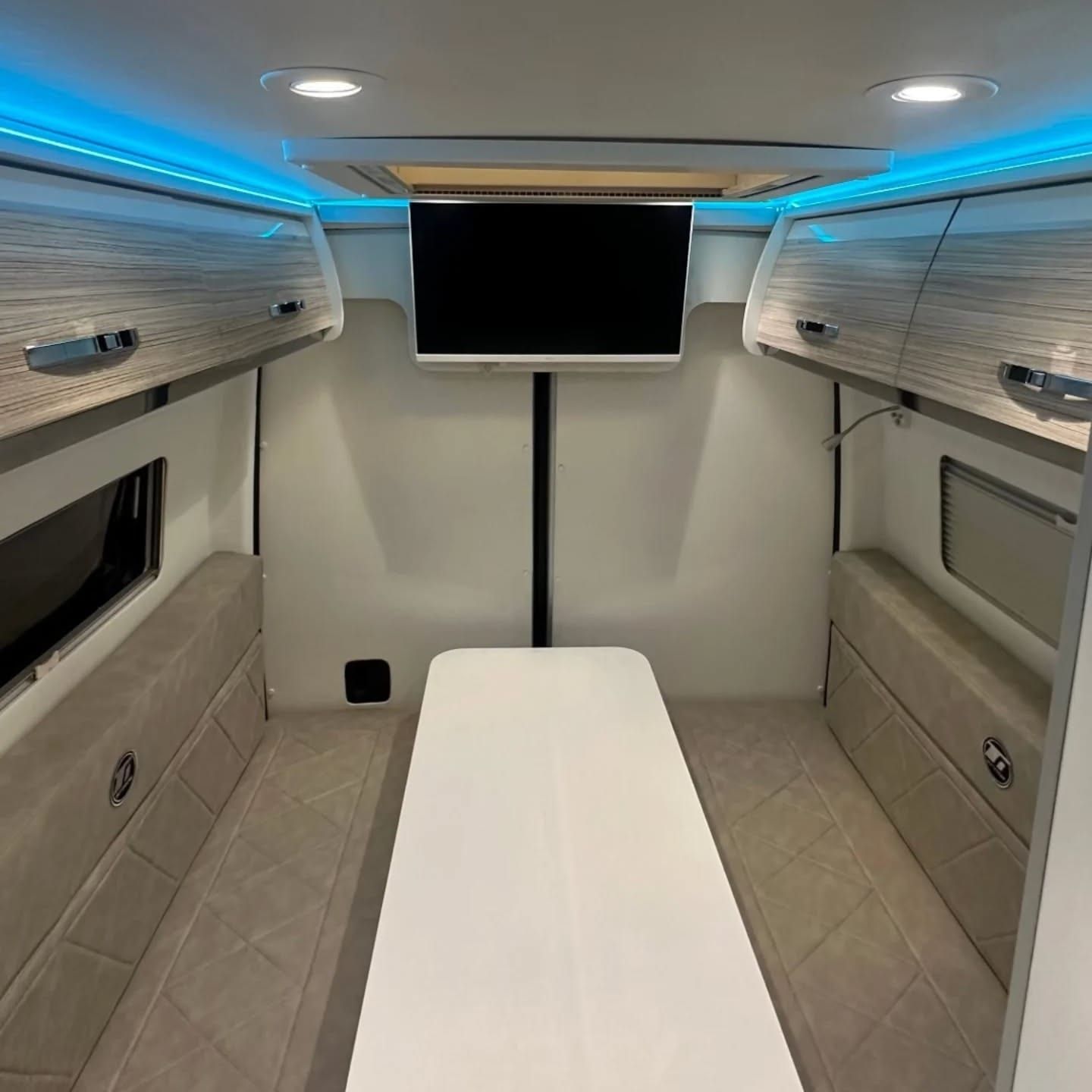 Longitudinal twin beds at the rear with a central TV and overhead lockers
