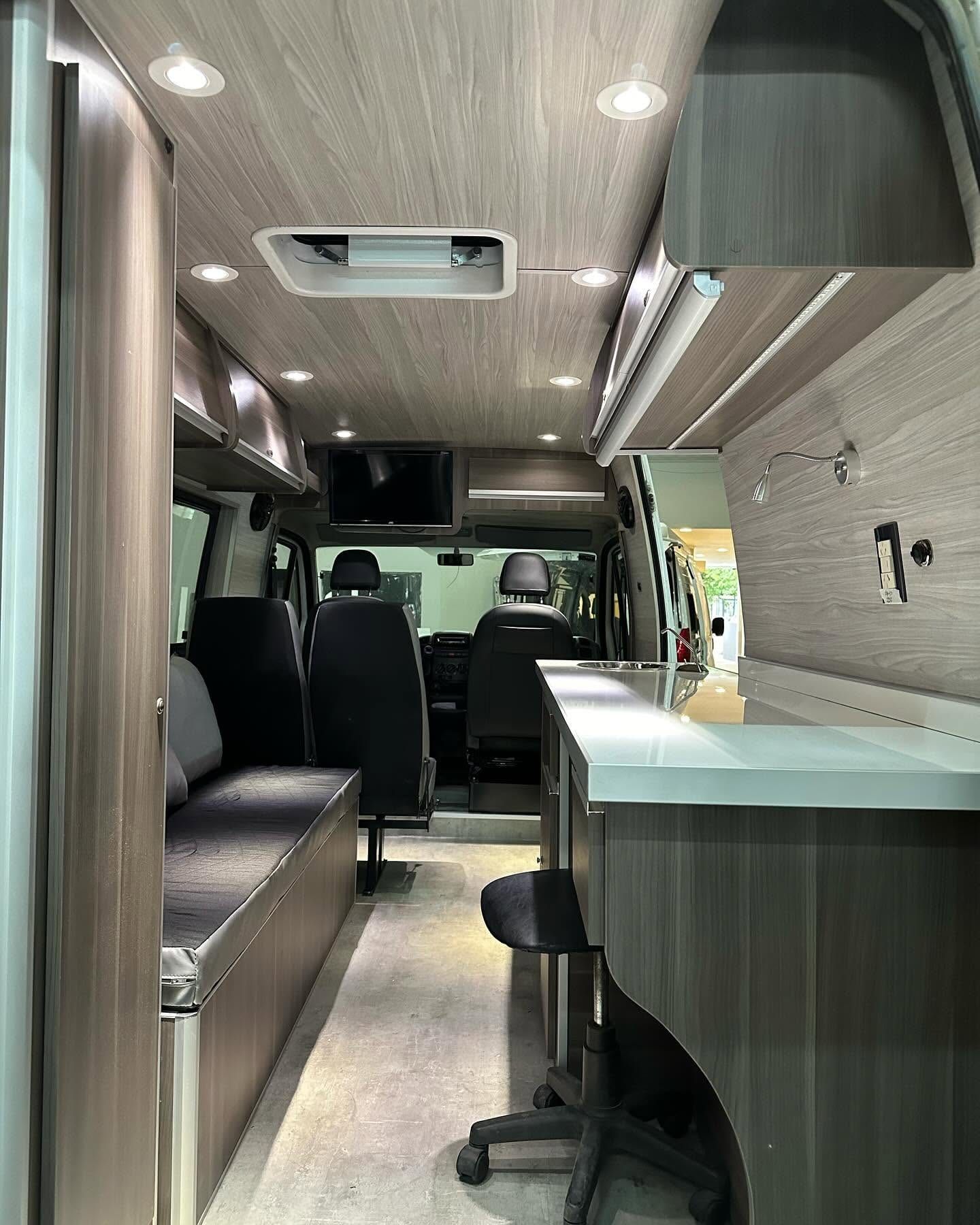 Interior de la Fiat Ducato oficina móvil: mesada de trabajo a la derecha, sillón cama a la izquierda y cabina al fondo