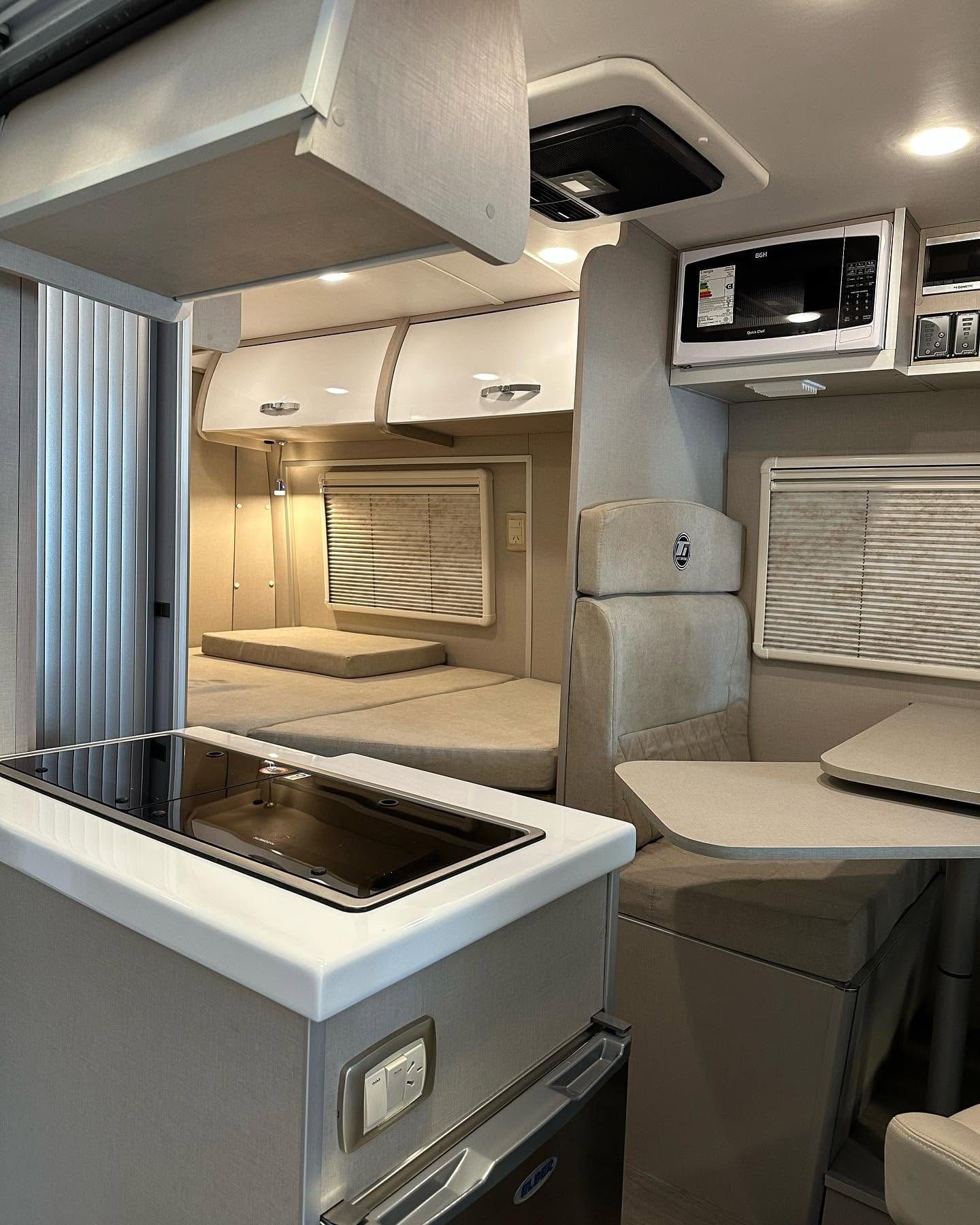 Interior de la Citroën Jumper: bloque de cocina en primer plano, comedor a la derecha y cama transversal al fondo