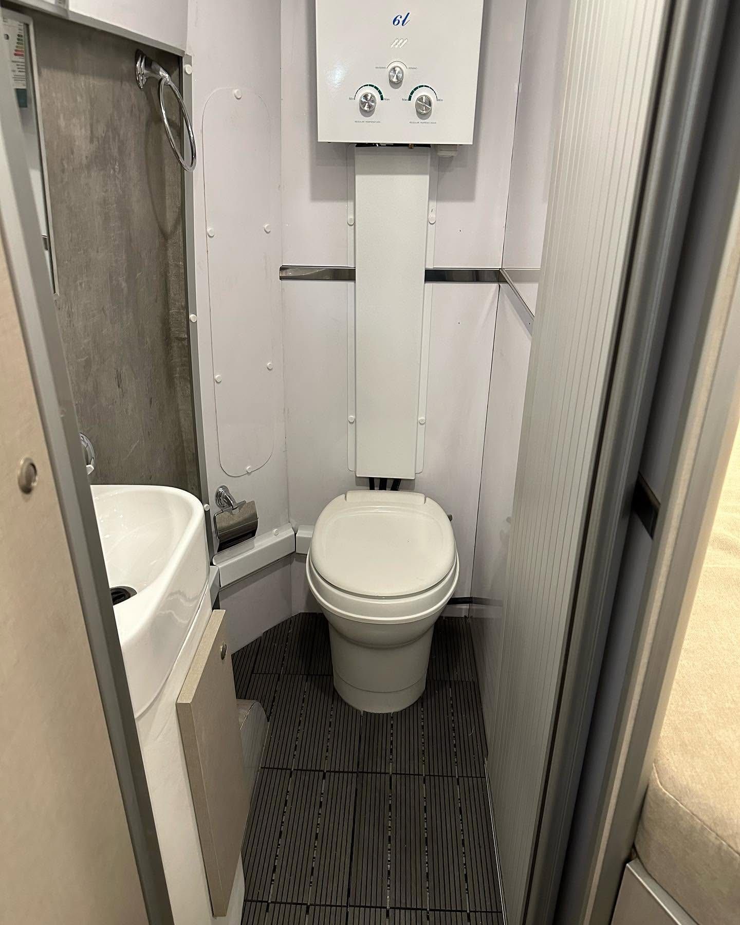Baño de la Citroën Jumper con inodoro químico, bacha de rincón y calefón a gas de 6 litros